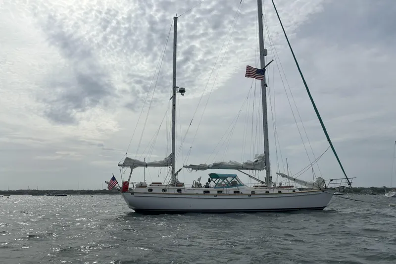 Shamrock Yacht Photos Pics 1984 Shannon 51' Center Cockpit sailboat on water, cloudy sky, American flag.