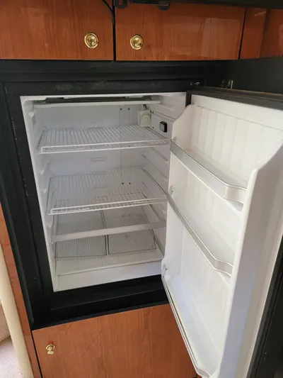  Yacht Photos Pics Open refrigerator inside 2000 Sea Ray 460 Sundancer yacht, featuring wooden cabinetry.