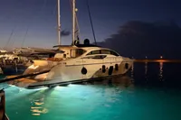 Luxurious 2009 Pershing 72' yacht illuminated at night in a serene harbor setting.