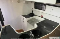 Compact yacht kitchen with black countertops, sink, and storage. Custom Murray Burns Dovell 62, 1999.
