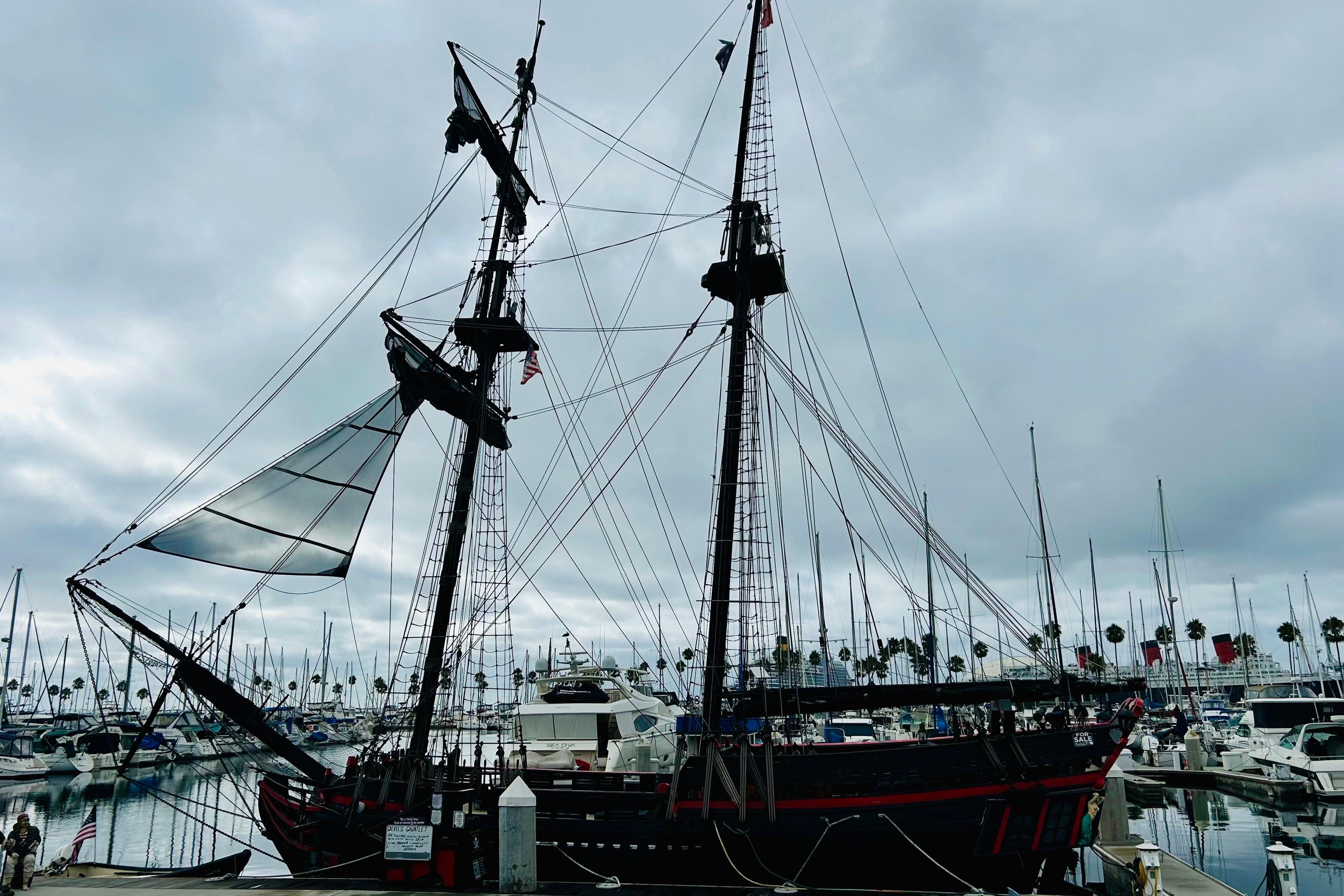 Vintage 1977 Custom Brigantine ship docked at a marina under cloudy skies.