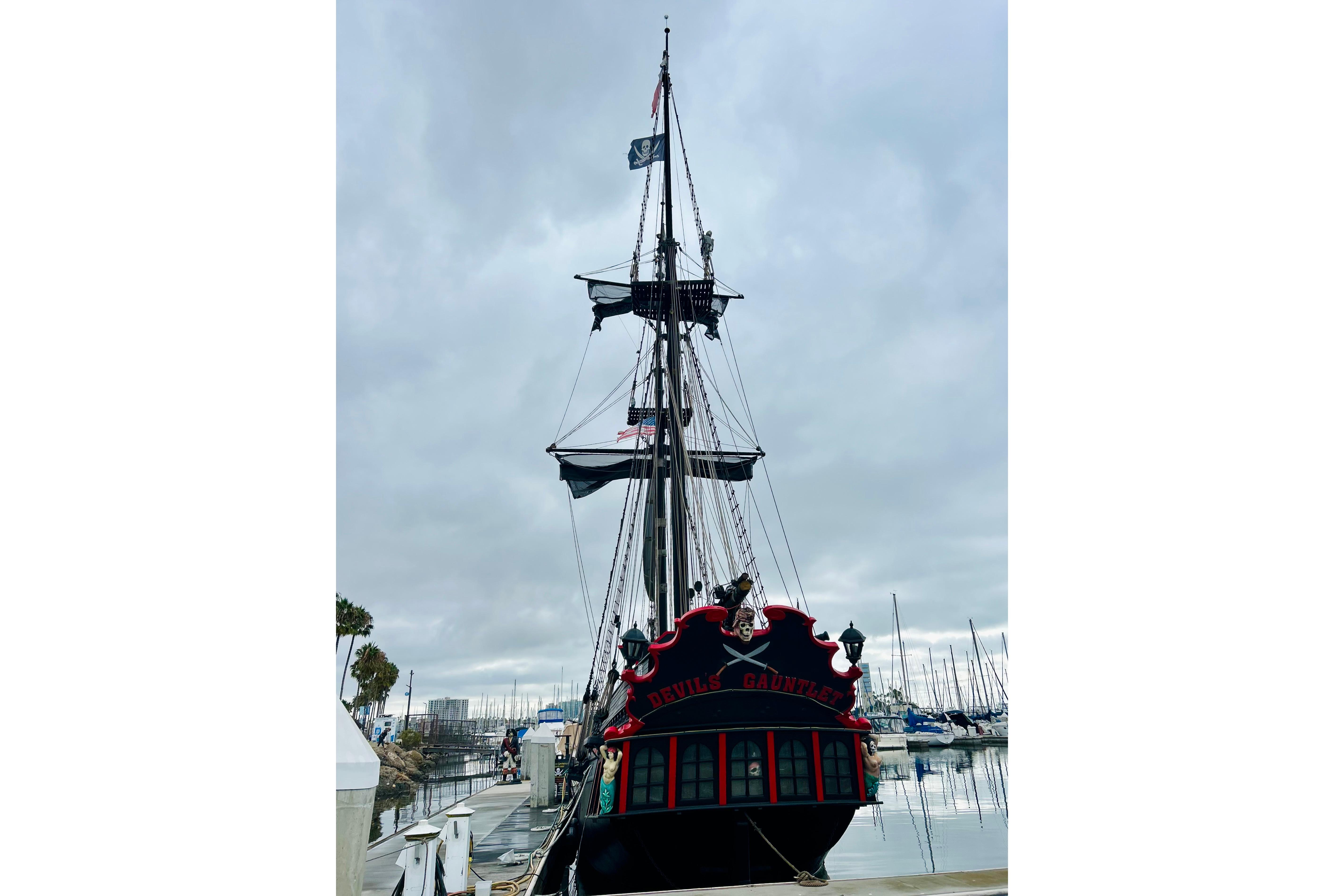 Vintage 1977 Custom Brigantine ship docked, featuring pirate-themed decor and flags.