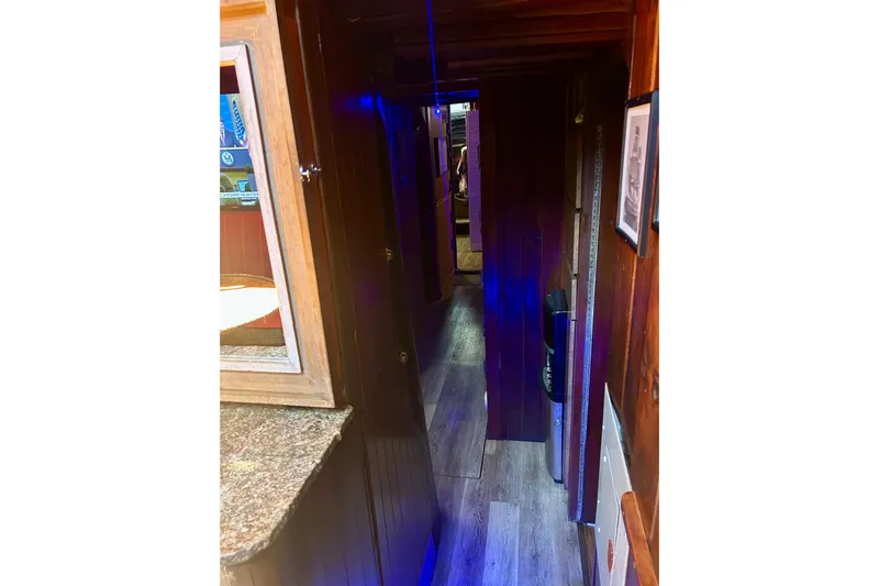Devil's Gauntlet Yacht Photos Pics Narrow wooden hallway inside a 1977 Custom Brigantine boat with blue lighting.