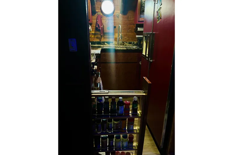 Devil's Gauntlet Yacht Photos Pics Cozy 1977 Custom Brigantine kitchen with porthole, spices, and wooden cabinetry.