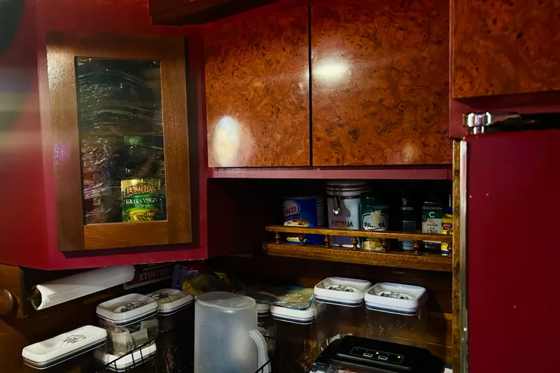 Devil's Gauntlet Yacht Photos Pics Kitchen storage in a 1977 Custom Brigantine, featuring wooden cabinets and various pantry items.