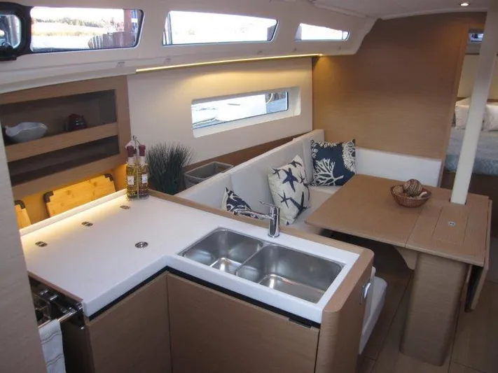  Yacht Photos Pics Modern interior of 2024 Jeanneau 380 sailboat with kitchen and dining area.