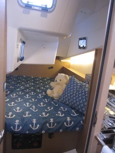  Yacht Photos Pics Cozy cabin interior of 2024 Jeanneau 380 sailboat with nautical-themed bedding.