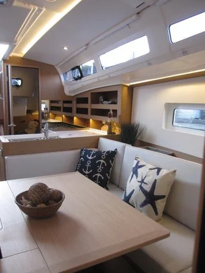  Yacht Photos Pics Modern interior of 2024 Jeanneau 380 sailboat with cozy seating and nautical decor.