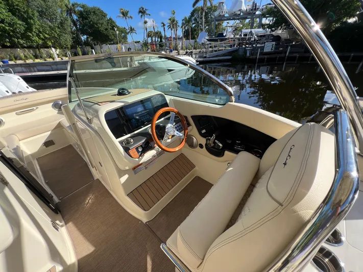  Yacht Photos Pics 2025 Chris-Craft Calypso 28 boat interior with steering wheel and dashboard, docked by palm trees.