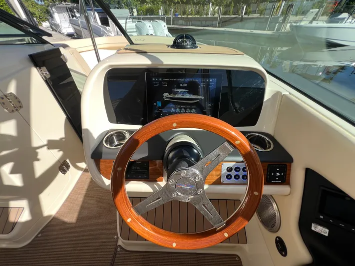  Yacht Photos Pics 2025 Chris-Craft Calypso 28 helm with wooden steering wheel and modern dashboard display.