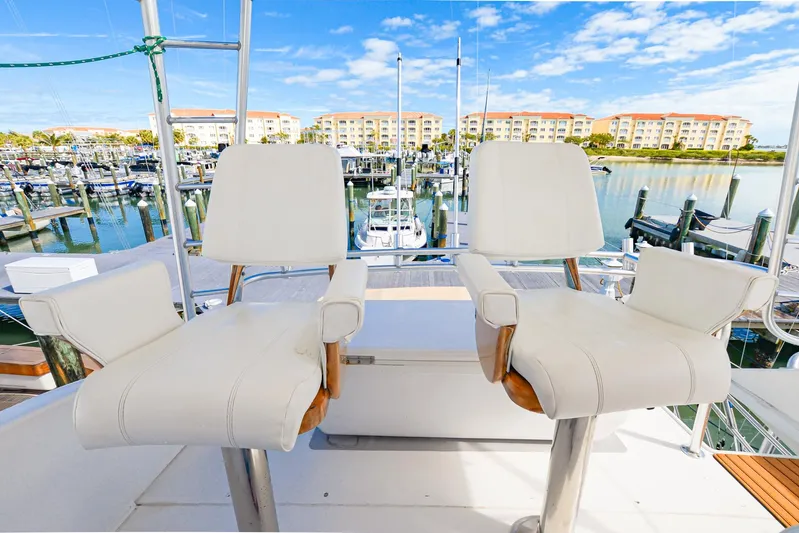 Sue-sea Yacht Photos Pics Two white captain's chairs on a 1999 Viking 55 Convertible yacht, overlooking a marina.