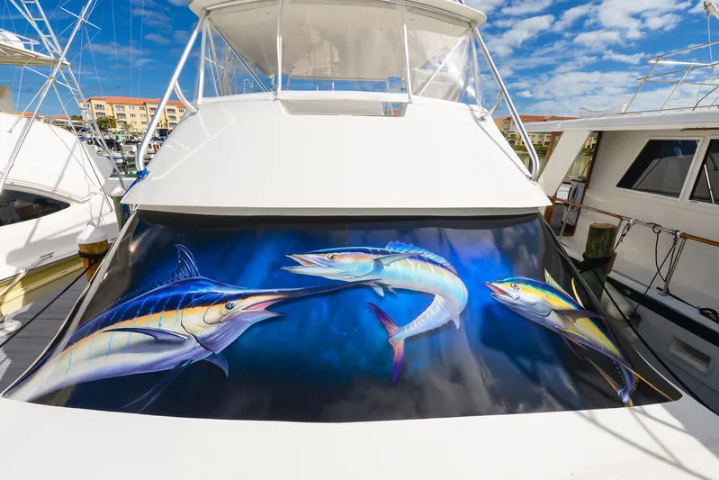 Sue-sea Yacht Photos Pics 1999 Viking 55 Convertible yacht with vibrant fish artwork on the stern, docked under a blue sky.