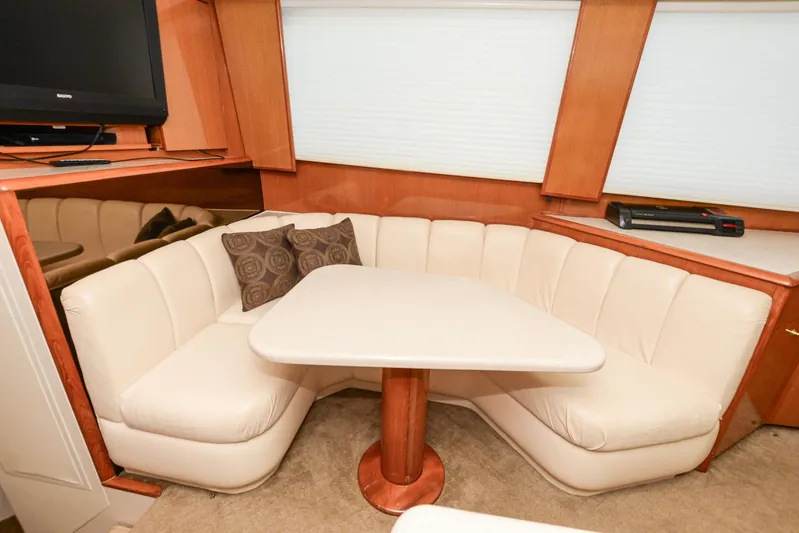 Sue-sea Yacht Photos Pics Cozy dining area in 1999 Viking 55 Convertible yacht with cream seating and wooden accents.