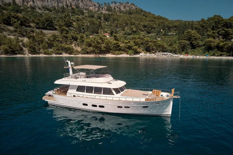 Sasga Yachts 68 Flybridge Yacht Photos Pics 2026 Sasga Yachts Menorquin 68 FB cruising on serene waters near a lush coastline.