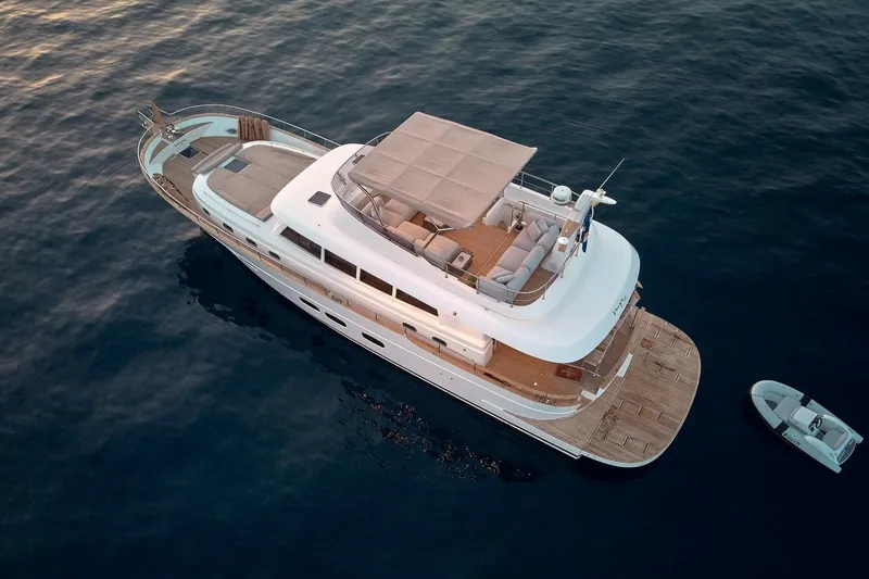 Sasga Yachts 68 Flybridge Yacht Photos Pics Aerial view of 2026 Sasga Yachts Menorquin 68 FB on calm water, with tender boat nearby.