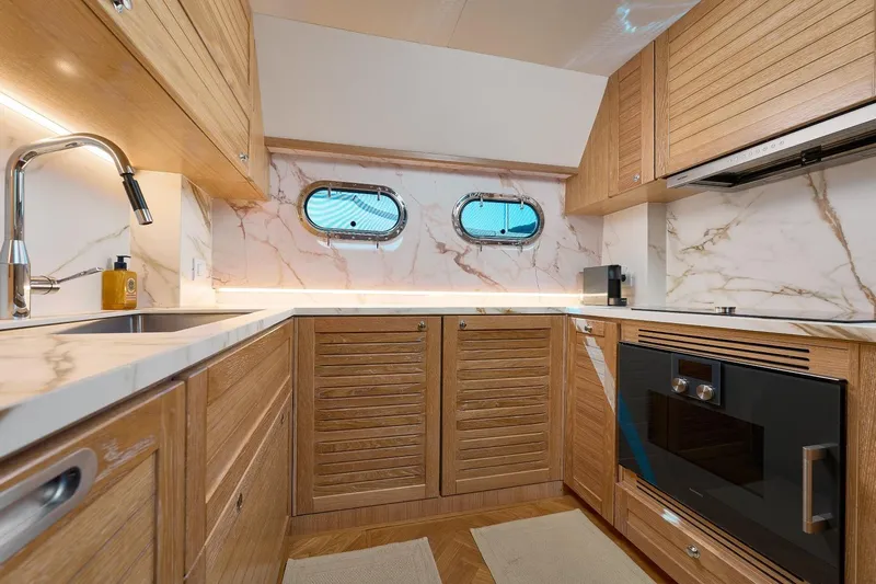 Sasga Yachts 68 Flybridge Yacht Photos Pics Luxurious kitchen interior of 2026 Sasga Yachts Menorquin 68 FB with wood and marble finishes.