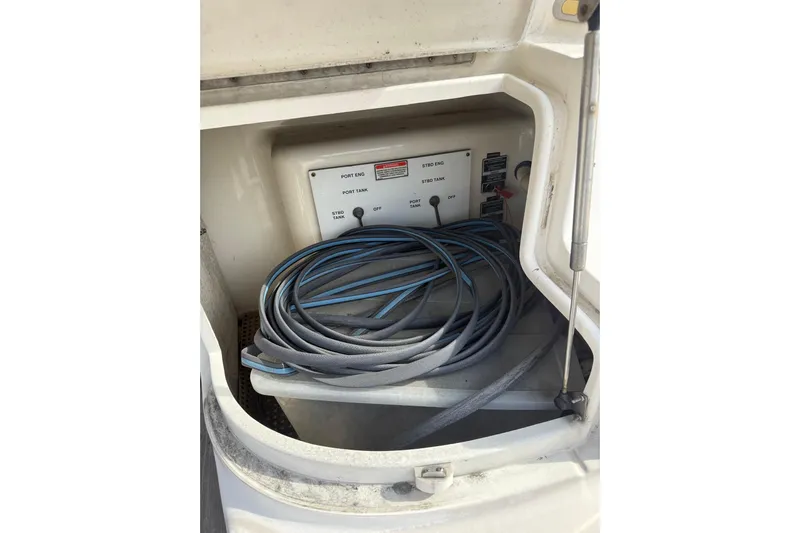Gambit Yacht Photos Pics Storage compartment of 2001 Sea Ray 560 Sedan Bridge with coiled cables and fuel manifold control panel.