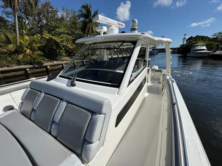  Yacht Photos Pics 2016 Boston Whaler 420 Outrage boat docked on a sunny day, surrounded by lush greenery.