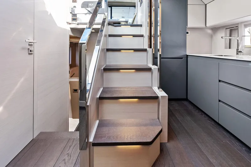 Niki Yacht Photos Pics Modern interior of 2024 Pershing 7X yacht with sleek staircase and kitchen area.