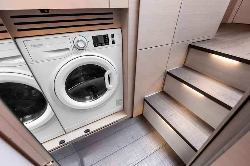 Niki Yacht Photos Pics Laundry area with washer in 2024 Pershing 7X yacht, featuring illuminated wooden stairs.