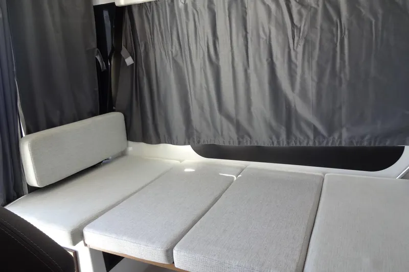 Blue Baby Yacht Photos Pics Interior seating area of 2022 Jeanneau Merry Fisher 895 Offshore with gray cushions and curtains.