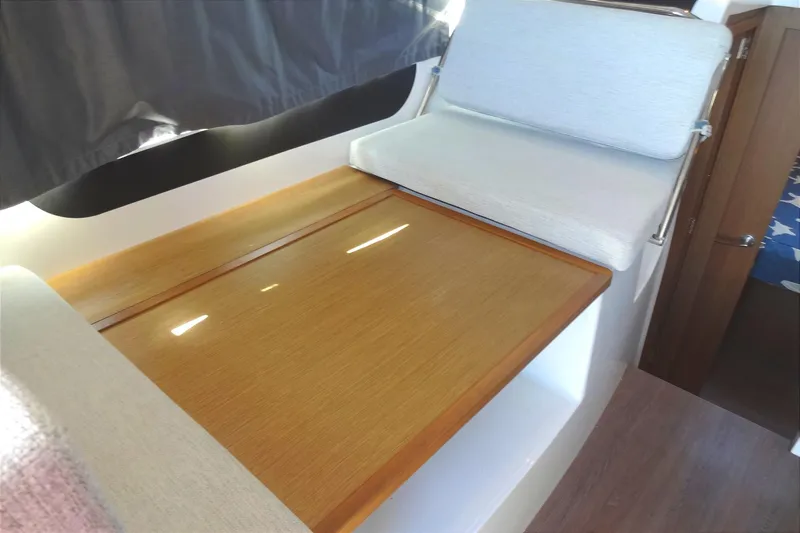 Blue Baby Yacht Photos Pics Interior of 2022 Jeanneau Merry Fisher 895 Offshore with wooden table and cushioned seating.