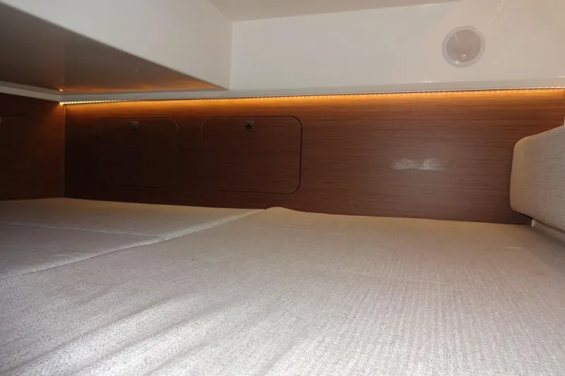 Blue Baby Yacht Photos Pics Interior cabin of 2022 Jeanneau Merry Fisher 895 Offshore, featuring cozy bedding and wood paneling.