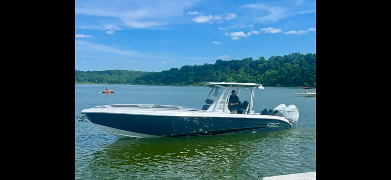 Adeline Yacht Photos Pics 2023 Glasstream 328 GS Xtreme boat on a serene lake with lush green backdrop.