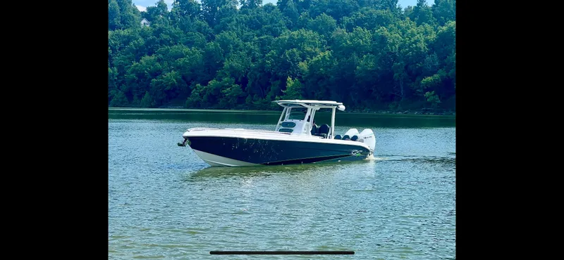 Adeline Yacht Photos Pics 2023 Glasstream 328 GS Xtreme boat on a serene lake with lush green trees.