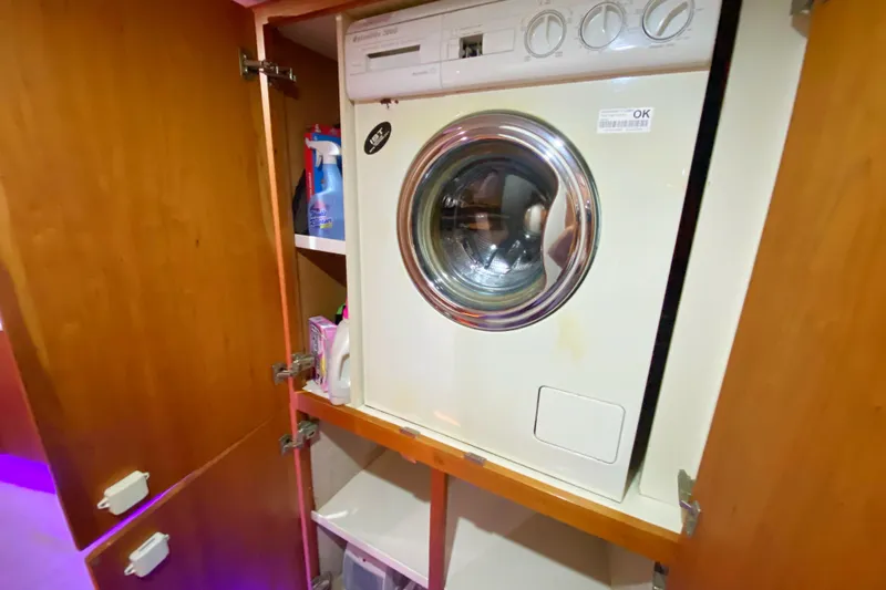 Nauti Boxer Yacht Photos Pics Laundry area inside 2003 Silverton 453 Motor Yacht with washing machine and storage shelves.