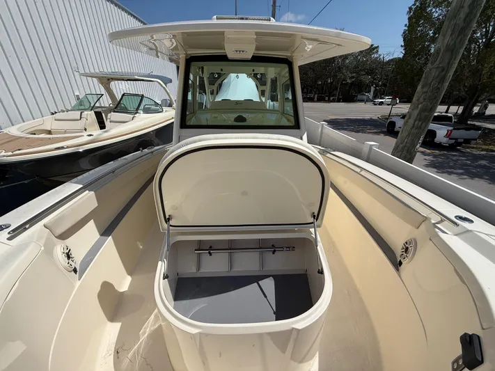  Yacht Photos Pics 2025 Scout 330 LXF boat with open storage compartment, docked outdoors.