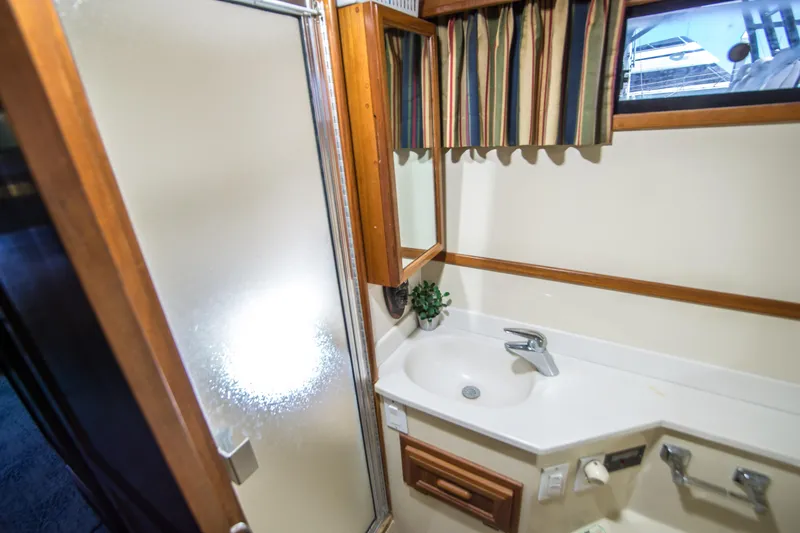 Coda Yacht Photos Pics 1989 Californian 55 Cockpit Motor Yacht bathroom with shower, sink, mirror, and striped curtains.