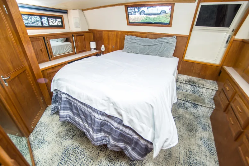 Coda Yacht Photos Pics Cozy bedroom in 1989 Californian 55 Cockpit Motor Yacht with wood paneling and carpeted floor.