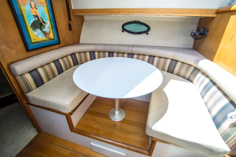 Coda Yacht Photos Pics Cozy dining area in 1989 Californian 55 Cockpit Motor Yacht with striped seating and round table.
