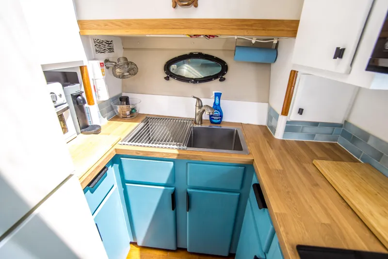 Coda Yacht Photos Pics Compact kitchen in 1989 Californian 55 Cockpit Motor Yacht with blue cabinets and wood countertops.