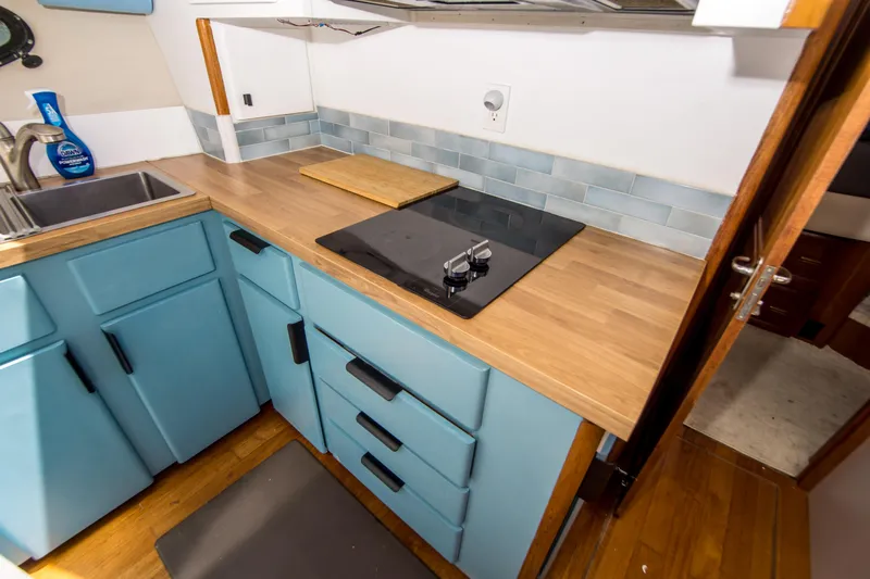 Coda Yacht Photos Pics 1989 Californian 55 Cockpit Motor Yacht kitchen with blue cabinets and modern cooktop.