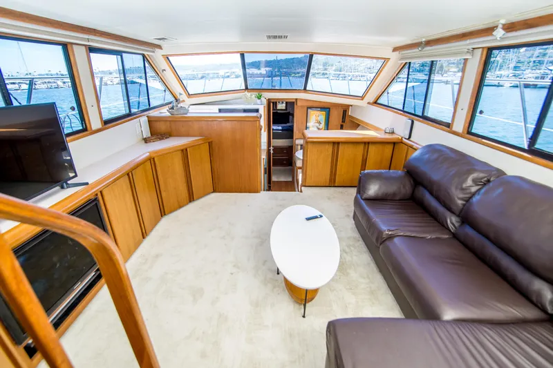 Coda Yacht Photos Pics 1989 Californian 55 Cockpit Motor Yacht interior with leather sofa, oval table, and panoramic windows.
