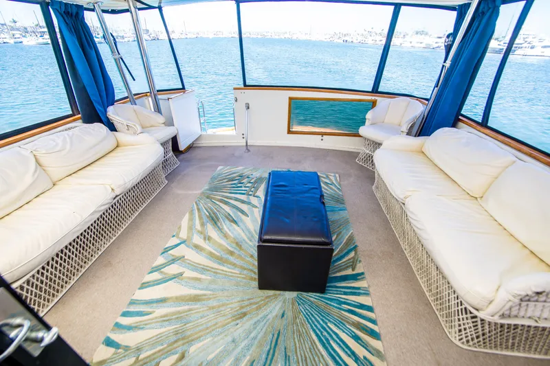 Coda Yacht Photos Pics 1989 Californian 55 Cockpit Motor Yacht interior with white seating, blue curtains, and ocean view.