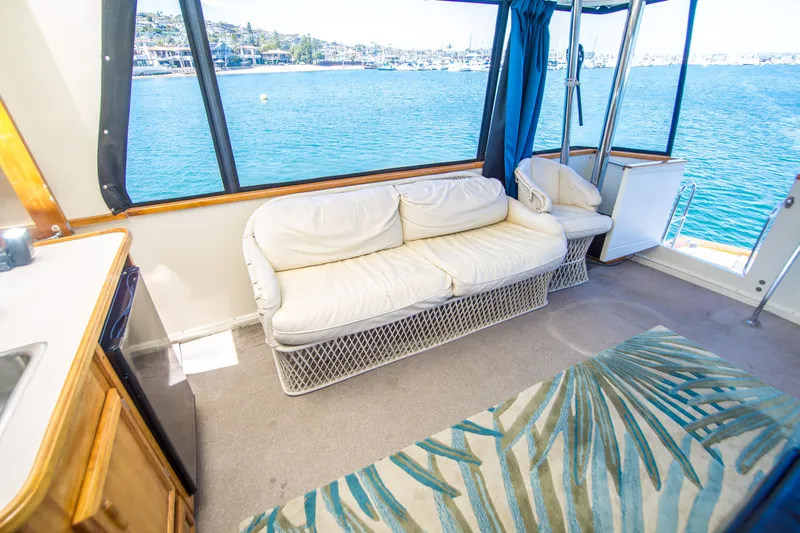 Coda Yacht Photos Pics 1989 Californian 55 Cockpit Motor Yacht interior with white seating, ocean view, and blue curtains.