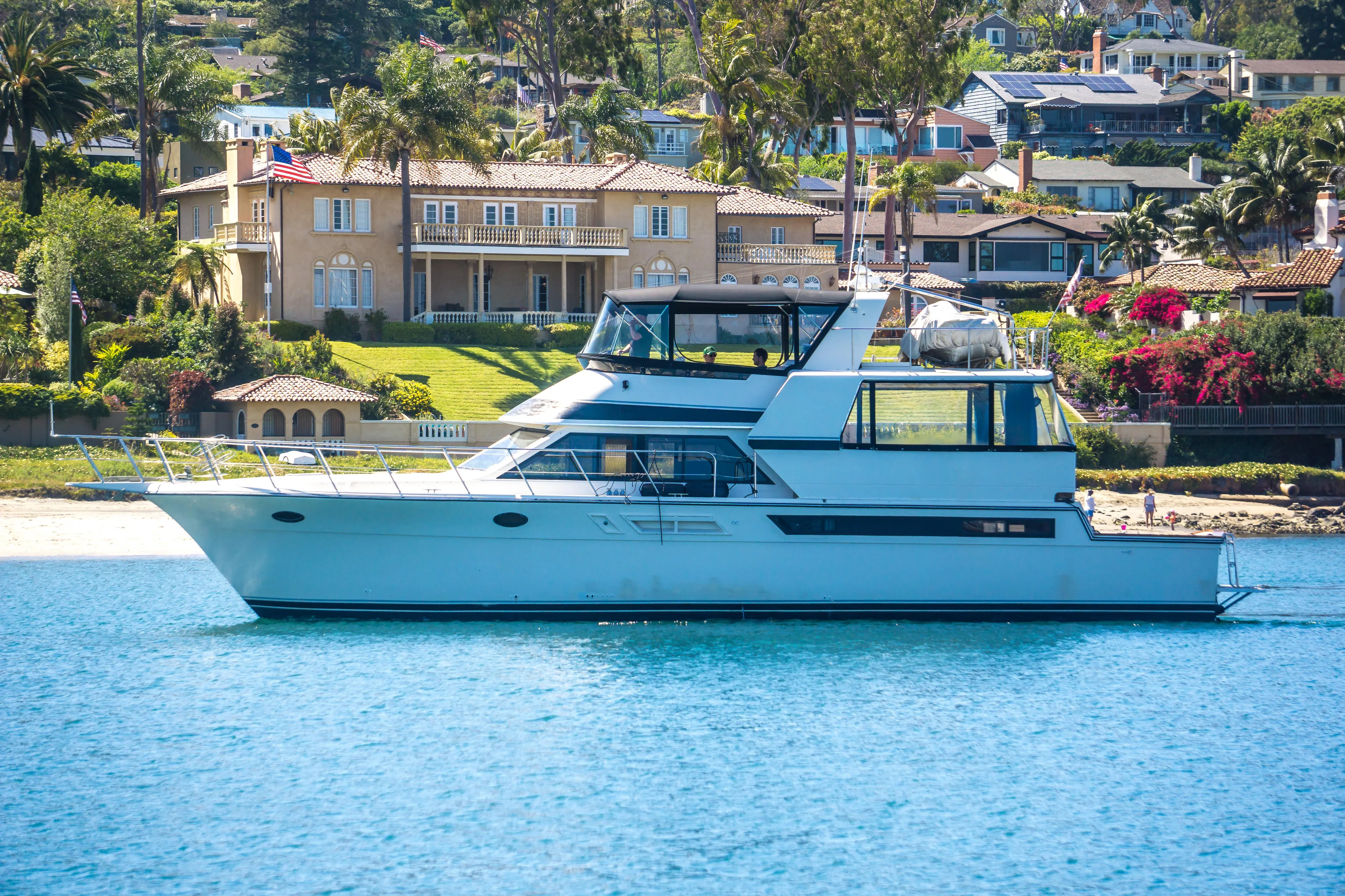 Coda Yacht Photos Pics 1989 Californian 55 Cockpit Motor Yacht cruising near luxurious waterfront homes.