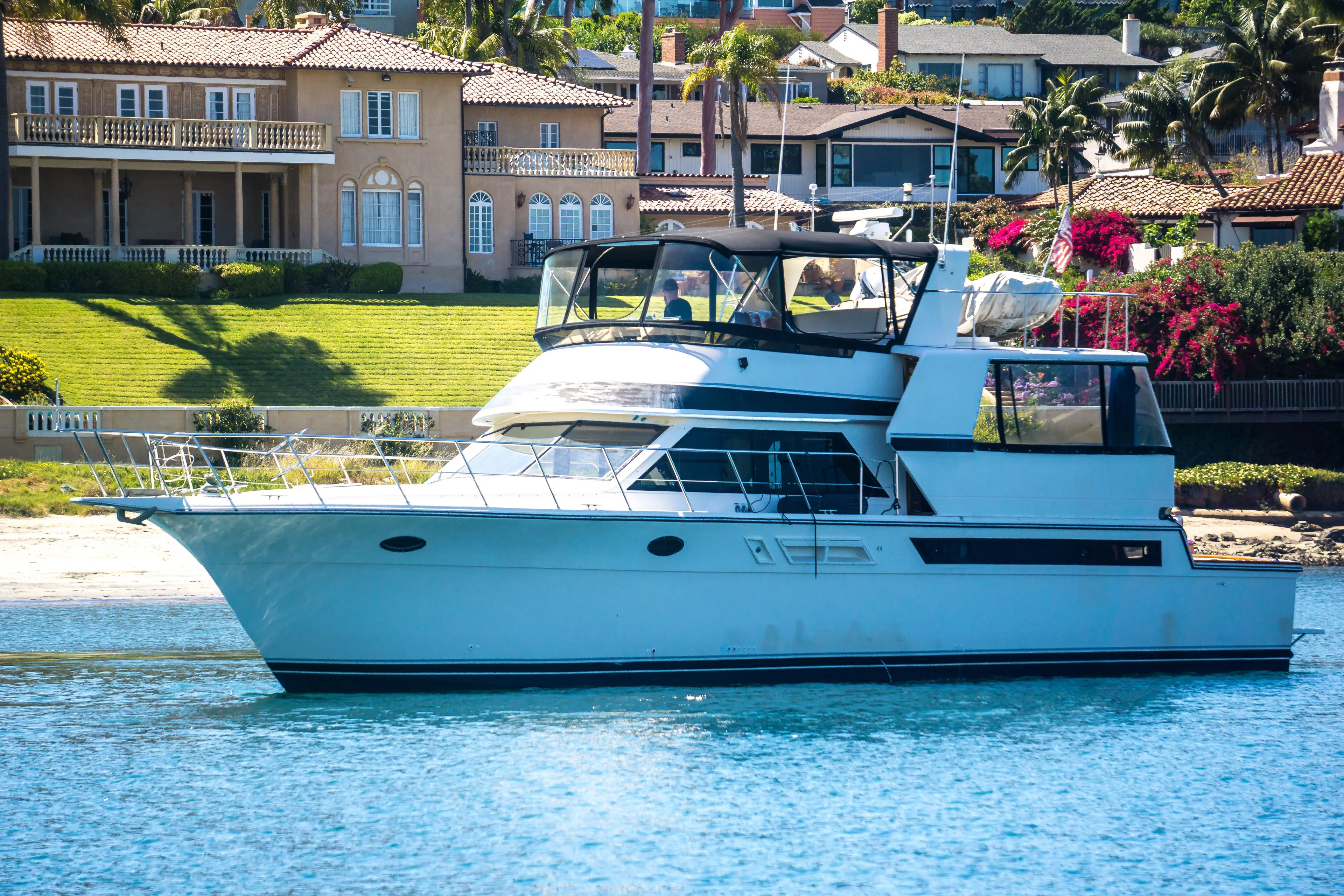 Coda Yacht Photos Pics 1989 Californian 55 Cockpit Motor Yacht on serene water, luxury homes in background.