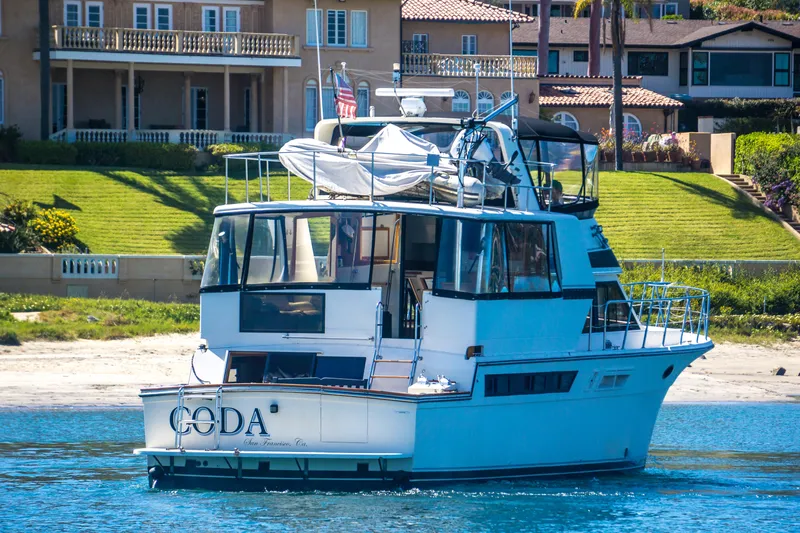Coda Yacht Photos Pics 1989 Californian 55 Cockpit Motor Yacht on water near luxury homes.