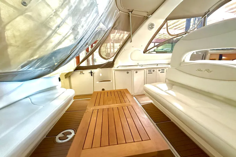 No Tan Lines Yacht Photos Pics Interior of 2000 Sea Ray 410 Sundancer with wooden table and white seating.