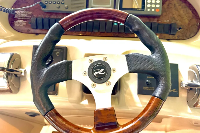 No Tan Lines Yacht Photos Pics Steering wheel of a 2000 Sea Ray 410 Sundancer boat, featuring wood and leather accents.