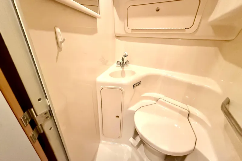 No Tan Lines Yacht Photos Pics Compact bathroom in 2000 Sea Ray 410 Sundancer yacht, featuring toilet and sink.