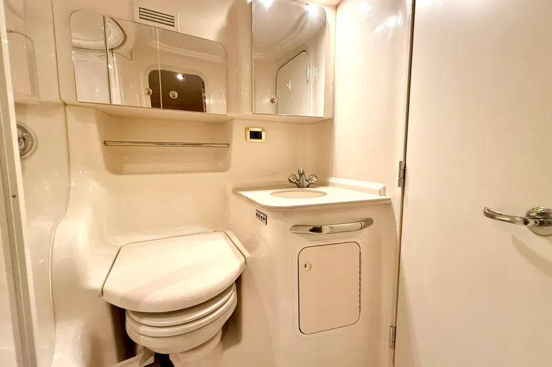 No Tan Lines Yacht Photos Pics 2000 Sea Ray 410 Sundancer bathroom with sink, toilet, and mirrored cabinet.