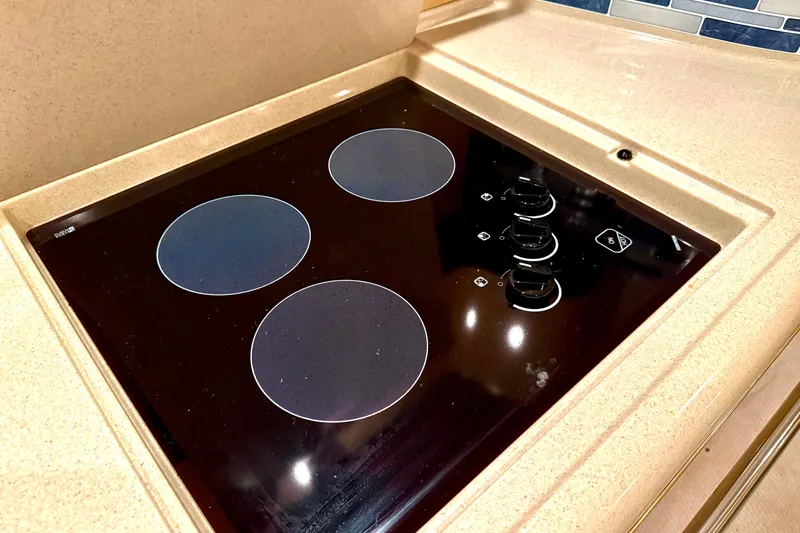 No Tan Lines Yacht Photos Pics Stovetop in 2000 Sea Ray 410 Sundancer yacht kitchen, featuring four burners and control knobs.