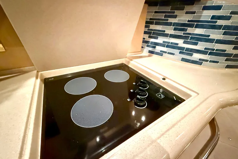 No Tan Lines Yacht Photos Pics Modern stovetop in 2000 Sea Ray 410 Sundancer yacht kitchen with stylish tile backsplash.