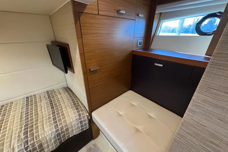  Yacht Photos Pics 2016 Tiara Yachts C44 Coupe interior with bed, TV, and wooden cabinetry.