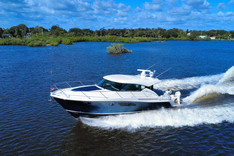  Yacht Photos Pics 2016 Tiara Yachts C44 Coupe cruising on a scenic blue lake under a clear sky.